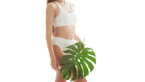Beautiful woman in white underwear over isolated white background. Close-up studio video of healthy young girl in swimsuit. Health and skin care, wellness, dieting and cosmetics concept.