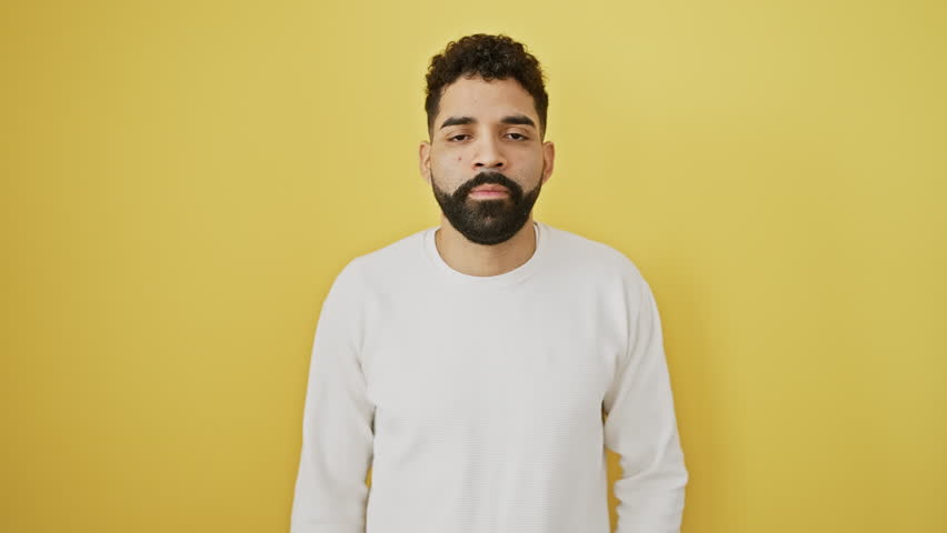 Affable young man offering a welcoming handshake in successful business greeting, smiling radiantly over isolated yellow background