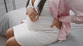 Exhausted young woman, pregnant and tired, sitting on bed, nursing a backache in her bedroom, grappling with the pains of expecting motherhood. - Powered by Shutterstock - Get 15% off with code: PIKWIZARD15