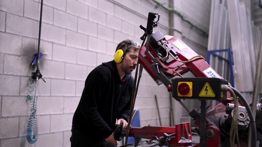 Video of a manual worker with protective headphones using a machine in a cnc modern factory
