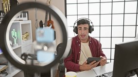 Captivating live video call, young, attractive hispanic man, ace radio reporter conveys news, on air from vibrant music studio, microphone in hand