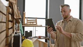 A focused man using a tablet in a well-equipped workshop with lumber and safety helmet. - Powered by Shutterstock - Get 15% off with code: PIKWIZARD15