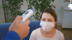 Health care. Doctor measures the temperature of patient wearing medical mask while sitting at home. Patient wearing mask with symptoms of high fever. Medical worker taking temperature - Powered by Shutterstock - Get 15% off with code: PIKWIZARD15