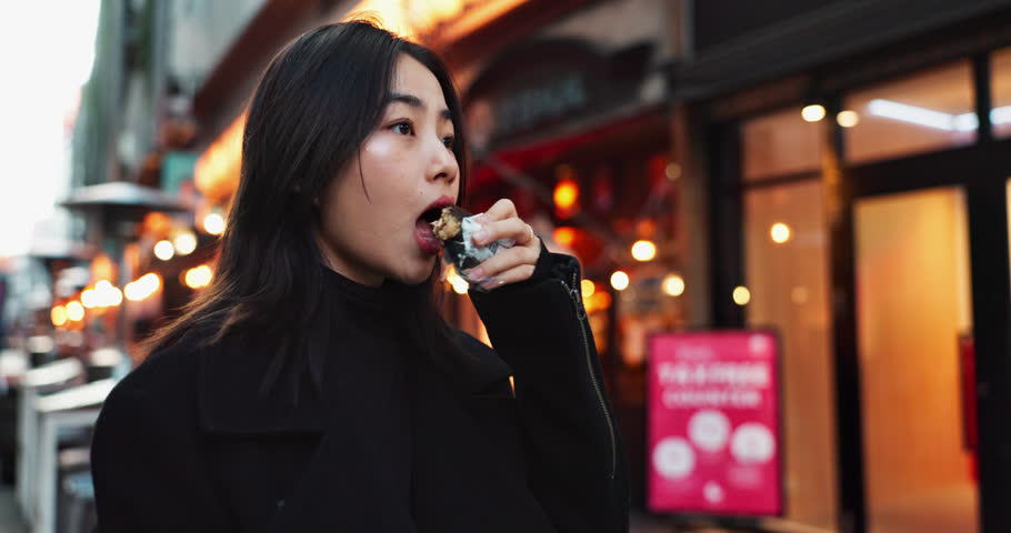 Travel, eating and Asian woman with onigiri in the city on exploring vacation, adventure or holiday. Hungry, food and young female person enjoying a Japanese snack or meal in town on weekend trip.