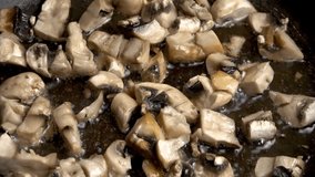 Adding finely diced onions to the mushrooms frying in a frying pan. Slow motion video.