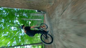 Vertical video. Bikes jumping on a ramp in the forest.