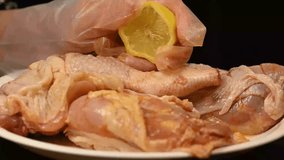 A hand squeezing a lemon on chicken leg for barbecue grilling with spices. 
