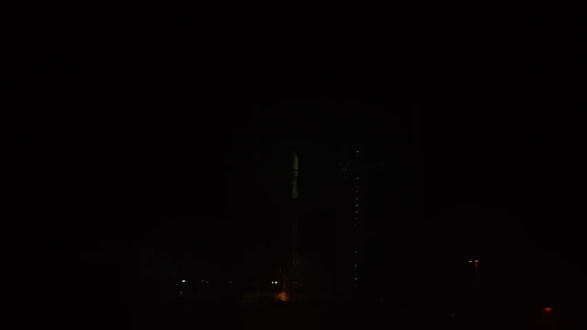 Beautiful close-up of a Space Rocket blasting off from launch pad at night as it flies to space on its mission to place communication satellites in earth orbit. Fire and flames reflected in water. 4K.