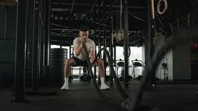 Active guy physical strength endurance exercise challenge powerful strong man squat pose training battle ropes at cardio workout in dark gym professional athlete exercise fitness sport club equipment - Powered by Shutterstock - Get 15% off with code: PIKWIZARD15