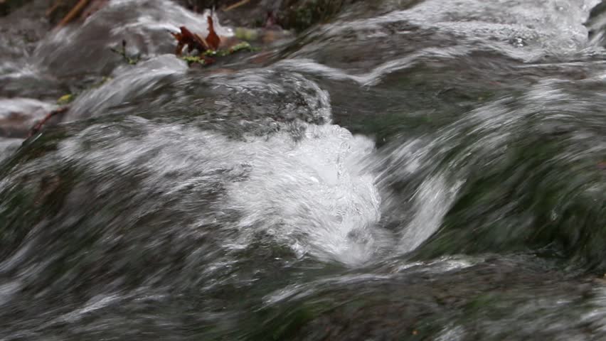 Fast moving water flowing over rocks in small stream. Winter. UK