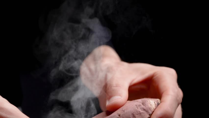 4K slow motion video of a baked potato slowly cracked open and steam coming out.