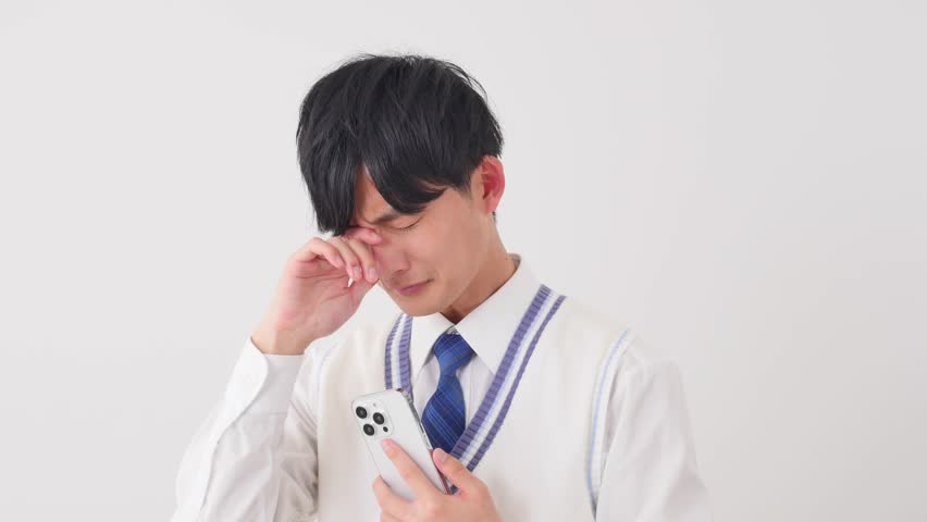Weeping Asian high school boy with the smartphone in white background Royalty-Free Stock Footage #3411272739