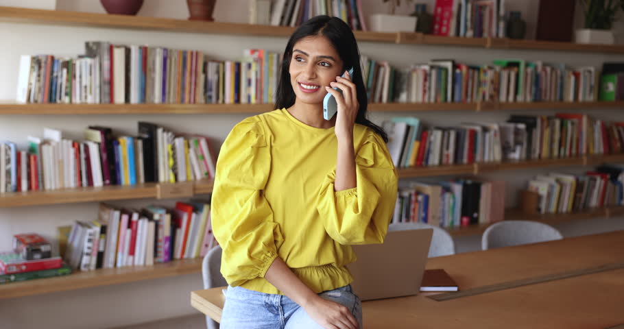 Indian businesswoman make call, talk on smart phone, work alone in cozy office, provide information to client remotely, lead personal or formal conversation during break at workplace. Communication Royalty-Free Stock Footage #3411283961