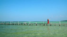 A pretty lady shoots a video of herself with an action camera on a selfie stick. Bright sunny day on the island. Phu Quoc Island. Selfie stick. Slow mothion..