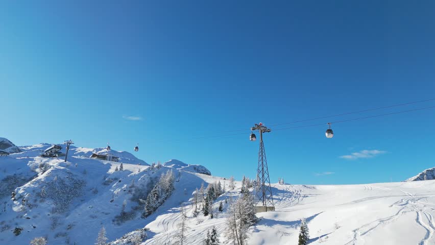Aerial ski lift Millenium Express carrier tracking shot to the top station at Nassfeld Skigebiet ski resort drone footage