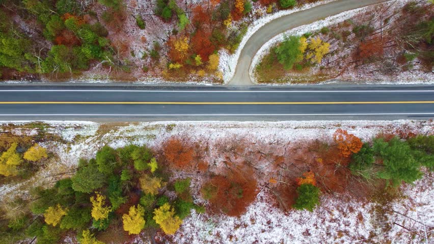 Topdown view Along asphalt road, Autumn colored trees and snow, New Hampshire, USA