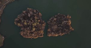 4K aerial video of drone flying above the lake with tow islands surrounded by autumn forest 