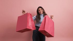 Happy hispanic woman showing pink shopping bags