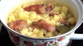 Stewed potatoes with smoked pork ribs are cooked in a saucepan on the stove. A fragrant, appetizing dish. Suitable for content about cooking, video recipes and home cooking.