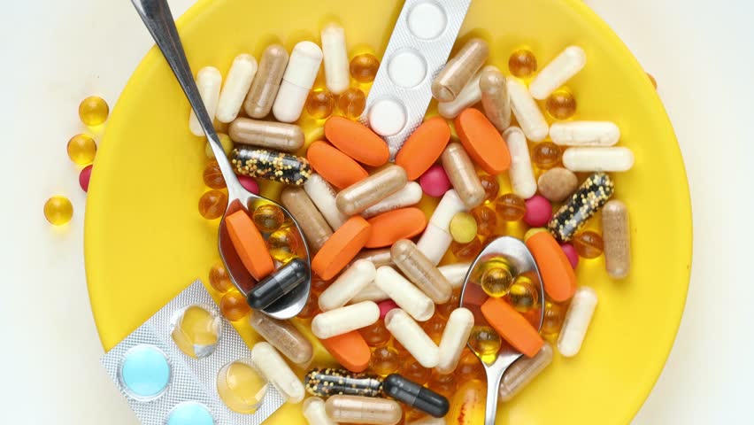 yellow plate full of medicines and hand with spoon mixing pills,`health concept. Excessive consumption of drugs and supplements, hypochondria, close up Royalty-Free Stock Footage #3411503003
