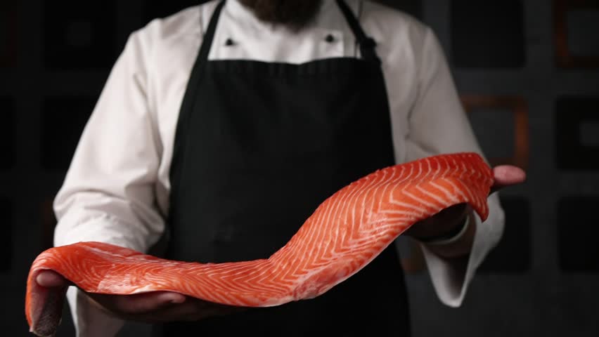 The chef holds a salmon fillet in his hands