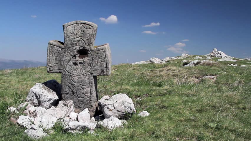 Ancient medieval stone cross with christian symbols on a high peak. West Bulgaria.