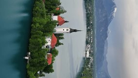 Aerial view of Bled lake with the Pilgrimage Church of the Assumption of Maria on a small island after sunset, Slovenia. Vertical video