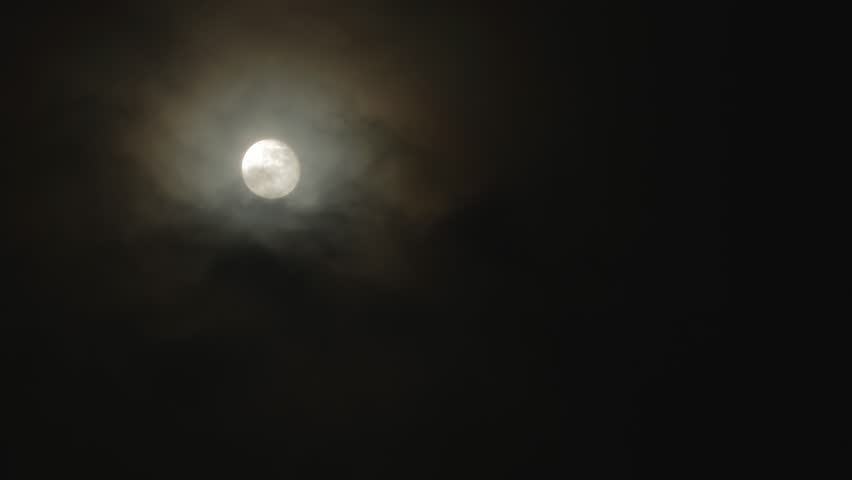 Full moon on a dark cloudy night with colored clouds flying in the sky in front of the moon. Corona - light optical phenomenon Royalty-Free Stock Footage #3411602453