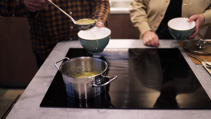 Pour a ladle of minestrone soup. Vegetarian soup dish is on table. Vegetarian healthy meal for dinner. Ready vegetable meal for lunch, hot and cozy soup for dinner at home. Soup with potatoes, carrots