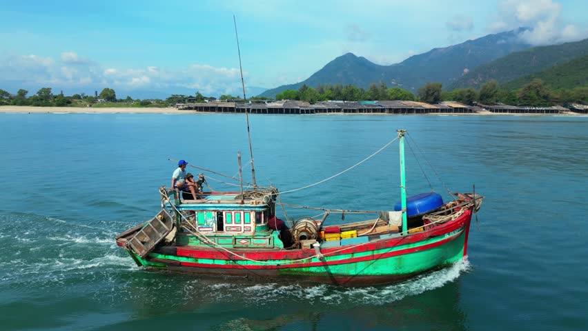 Fishermen Nha Trang in Vietnam are sailing on a against the backdrop of a beautiful landscape and a wonderful mountains on a sunny day. On sunny morning, fishing boat hurries to sea to catch seafood