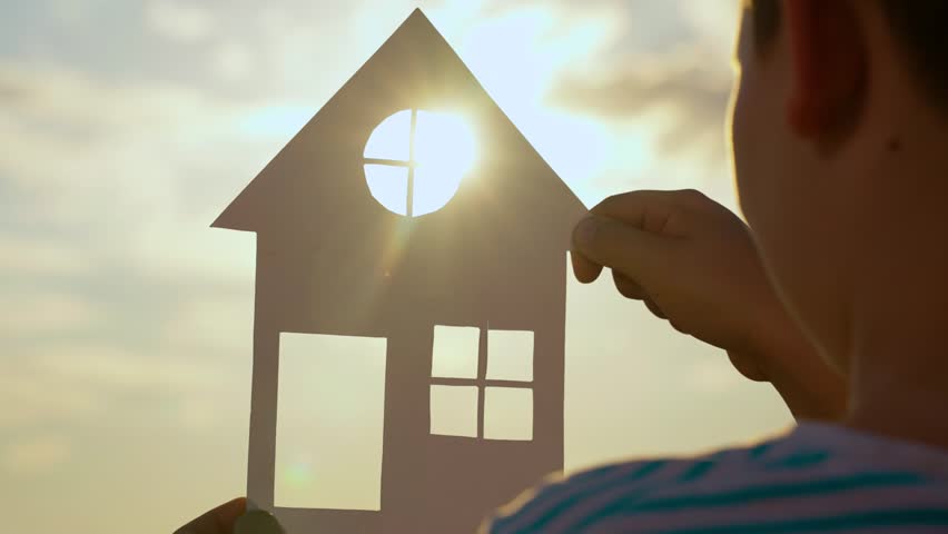Home for children, parents. Hands of child boy hold paper house at sunset, sun shines through window. Symbol of home for family, happiness. Concept of building house for child. Dream of buying house Royalty-Free Stock Footage #3411703947