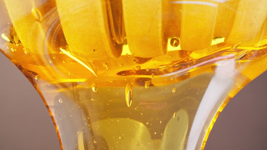 Honey dripping from wooden honey spoon. Healthy organic food concept. Tasty honey flowing from wooden dipper scoop. Close-up in 4K, UHD
