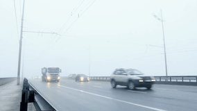 Misty city traffic. Vehicles appear from the dence fog on a bridge.