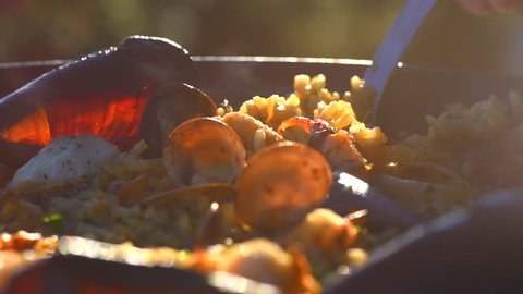 Seafood Paella cooking. Traditional Spanish paella with prawns, mussels and fish. Person cooking fresh delicious paella closeup. 4K UHD slow motion video