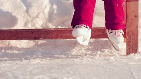 Ice rink recreation area. Girl in sliding universal ice skates sitting on a wooden bench and enthusiastically swinging her legs in anticipation of ice skating - Powered by Shutterstock - Get 15% off with code: PIKWIZARD15