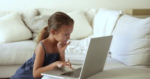 Cute little girl spend free time on internet use laptop, learn new apps, enjoy creative hobby, develop skills on-line, play game or choose information on website. Younger gen Alpha using modern tech