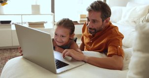 Dad and little daughter websurfing, search information, choose goods, buy e-services, enjoy electronic commerce retail services using laptop spend free time together at home. Internet usage, ecommerce