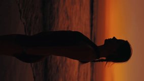 Vertical Video. Relaxed Charming Girl in Sportswear Standing Outside on the Sunset, Enjoying Meditation with Hands in Namaste. Sporty Girl Training Outside. Tranquil Woman Standing on the Sea Beach