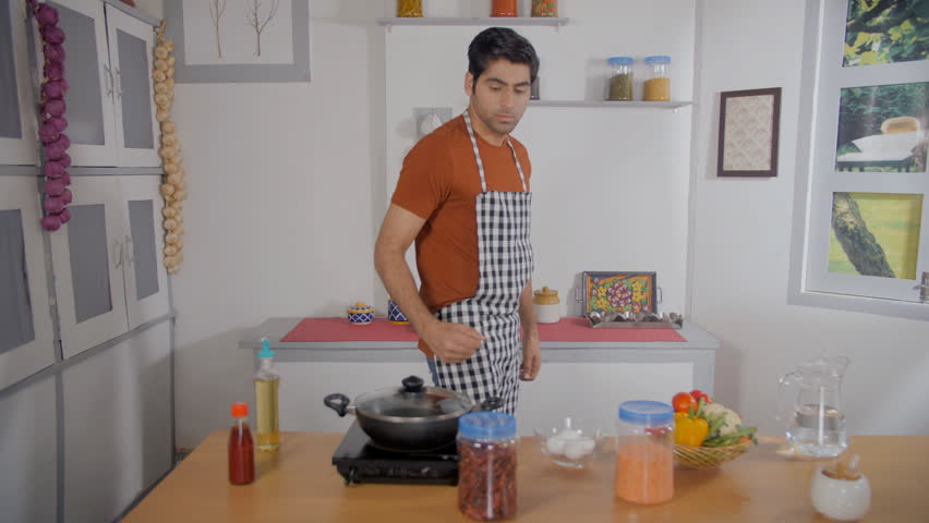 Indian man putting containers on shelves - tidying up, maintaining hygiene, food storage, organized kitchen, pantry. Attractive young man cleaning up after cooking - housework, kitchen organization... Royalty-Free Stock Footage #3412055855