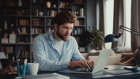 speed up portrait of young man with beard in blue shirt sits at table in home office, typing on keyboard non stop, smiling and staying focused - Powered by Shutterstock - Get 15% off with code: PIKWIZARD15