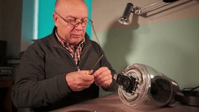 elderly man with a screwdriver. repair of consumer electronics. kettle repair. slow motion video. High quality video in 4k