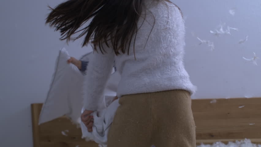 Fun Playful Activity of Children in Pillow Fight, Feathers Flying in Super Slow Motion, little brother throws pillow on the side of sister in bedroom
