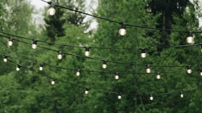 Light bulbs hang on wires in the yard and illuminate the surrounding space. Shooting the decor in motion - Powered by Shutterstock - Get 15% off with code: PIKWIZARD15