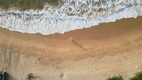 Aerial view, woman strolls sandy shore, tranquil waves wash over beach, leisure stroll, serene seascape, clear summer day, overhead perspective showcases solitary figure, coastline, ocean - Powered by Shutterstock - Get 15% off with code: PIKWIZARD15