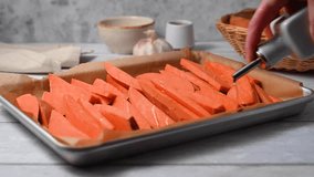 Cooking sweet potato wedges, fries on a baking pan. Hand adding oil. - Powered by Shutterstock - Get 15% off with code: PIKWIZARD15