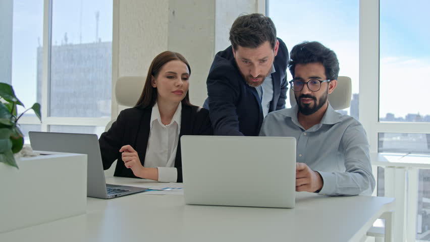 Diverse team corporate coworkers working laptops in office male business coach mentor boss businessman helping employees with computer work training new workers help interns check explain data project Royalty-Free Stock Footage #3412491751