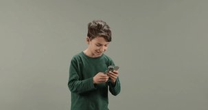 Cute kid holding smart phone watching funny video, laughing. Little boy using cellphone having fun