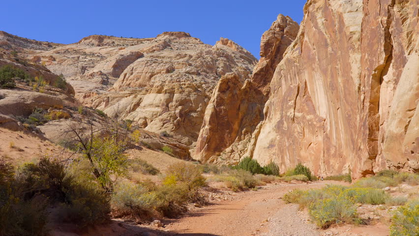 Establishing shot of mountain trail with red rocks in Grand Wash Trail, Capital Reef National Park, Utah, North America. Day time on October 2023. ProRes 422 HQ.