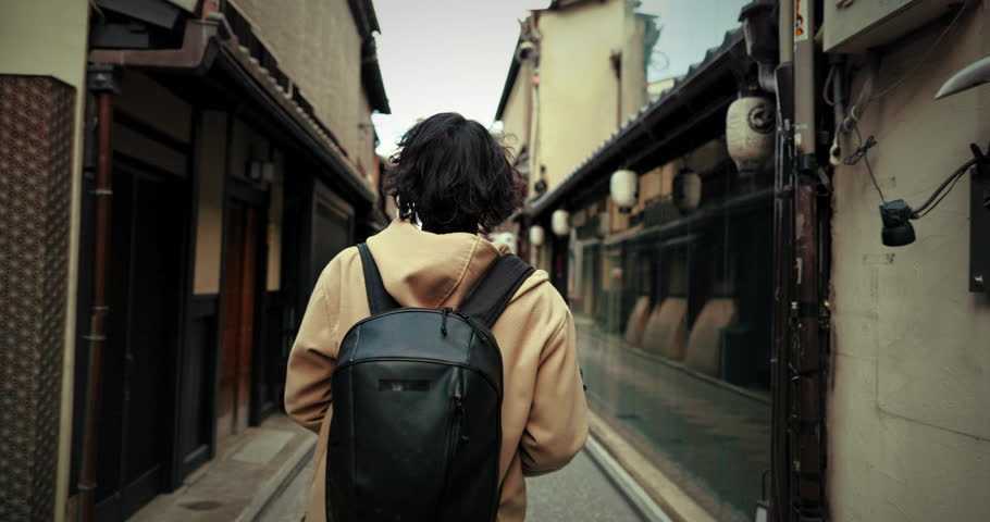 Person, walk and Japanese street on holiday for explore city, international travel or learning culture. Traveler, back view and stroll or discover architecture buildings, outdoor journey or adventure