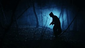 Mysterious dark figure in the night foggy forest. Silhouette of an unrecognizable man in a tunic with a hood. - Powered by Shutterstock - Get 15% off with code: PIKWIZARD15